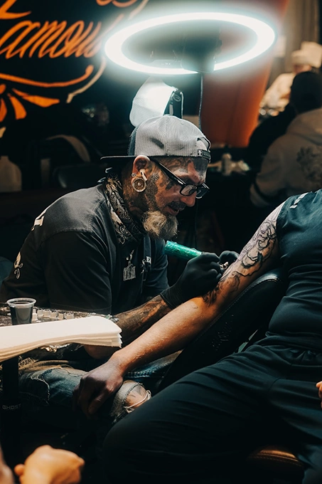 Tatuoija työstää tatuointia asiakkaan käsivarteen studiossa